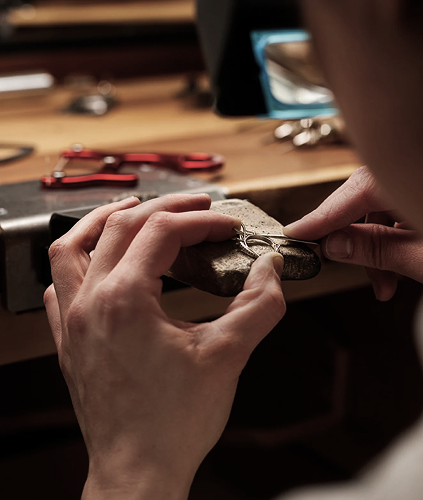 A jeweler's hands setting a ring at the bench